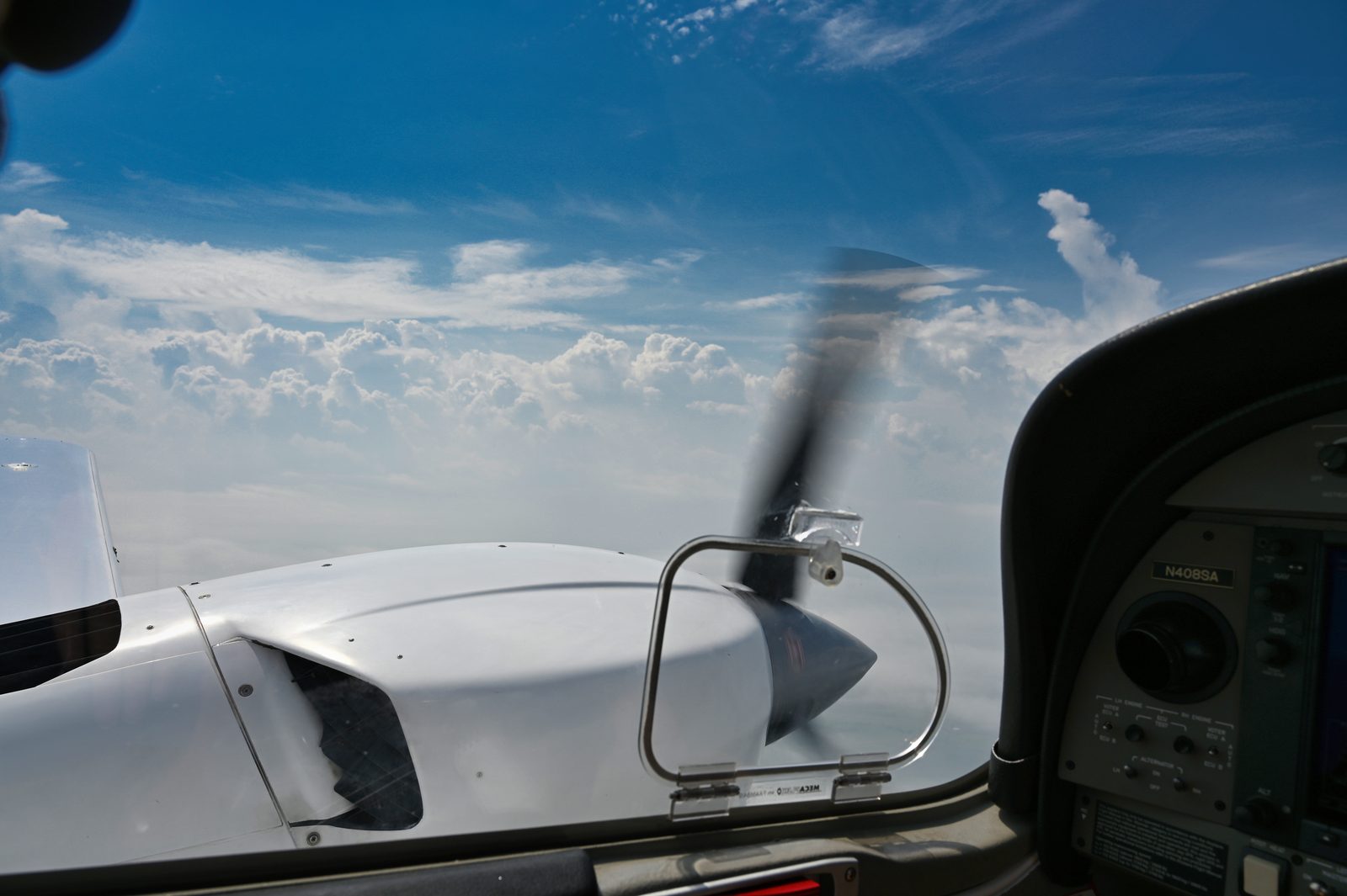 View from the cockpit over the nose and spinning propeller in clear sky
