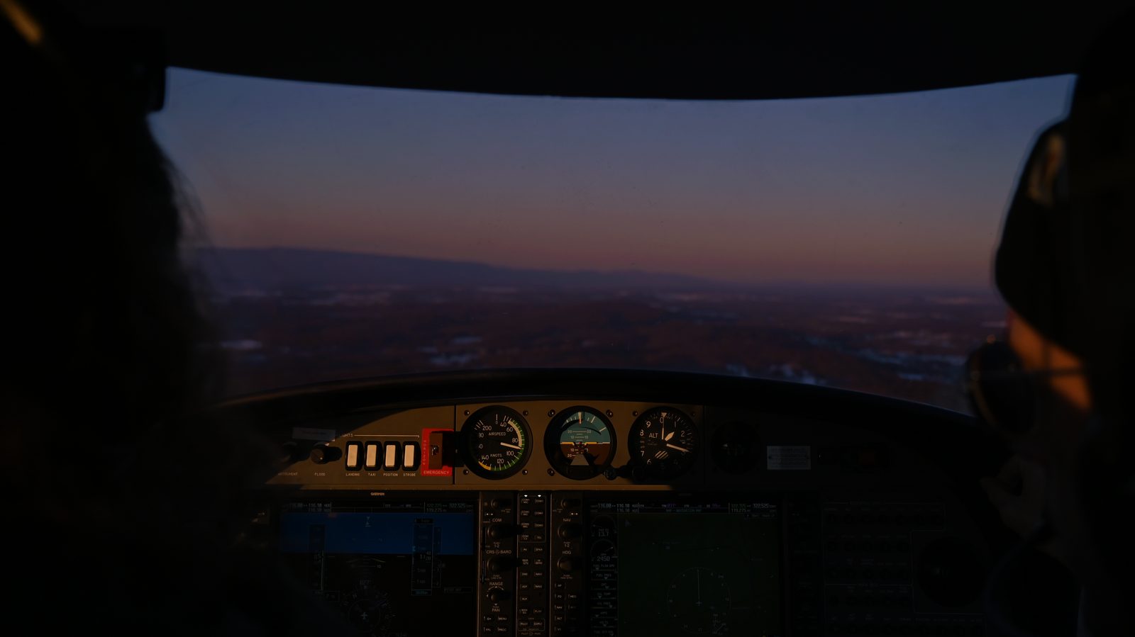 Cockpit panel glowing at dusk with the horizon ahead