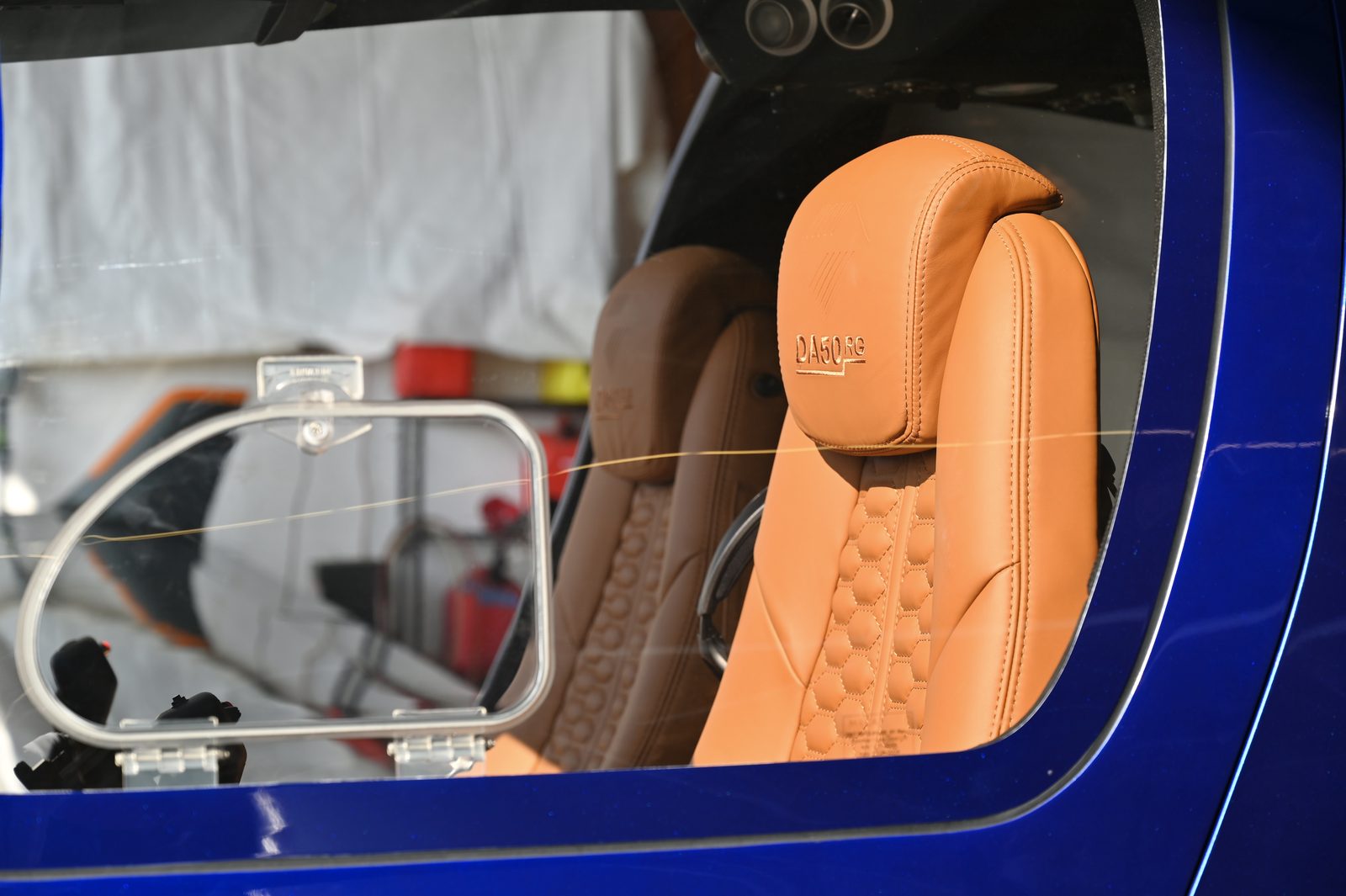 Tan leather seat framed by a blue fuselage and open canopy