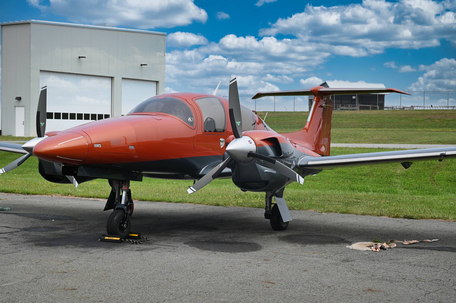 Orange twin-engine aircraft on the ramp under a bright sky