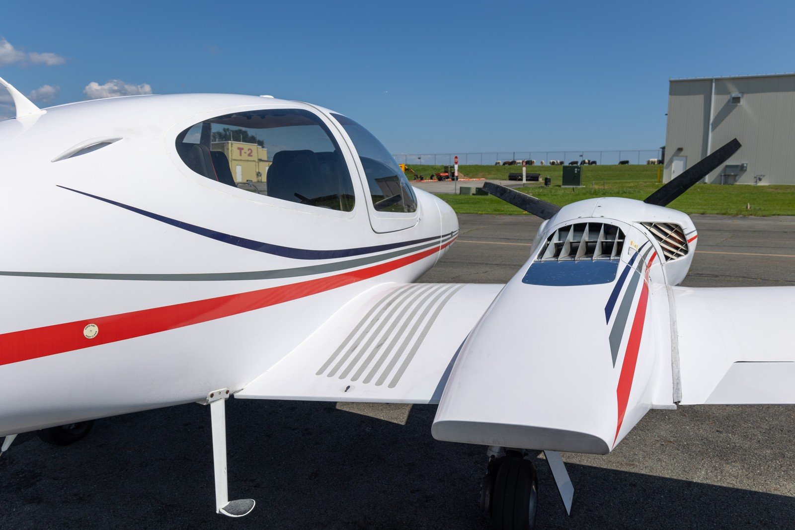 Red-striped Diamond single seen from the wing, three-blade prop and blue sky