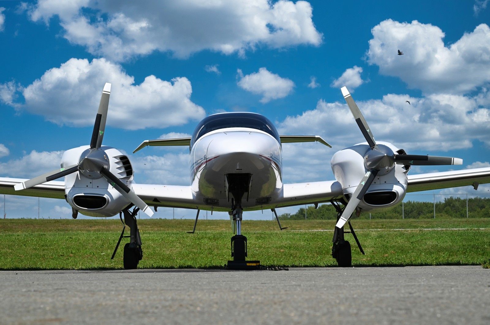 Diamond twin with both propellers facing the camera beneath towering clouds