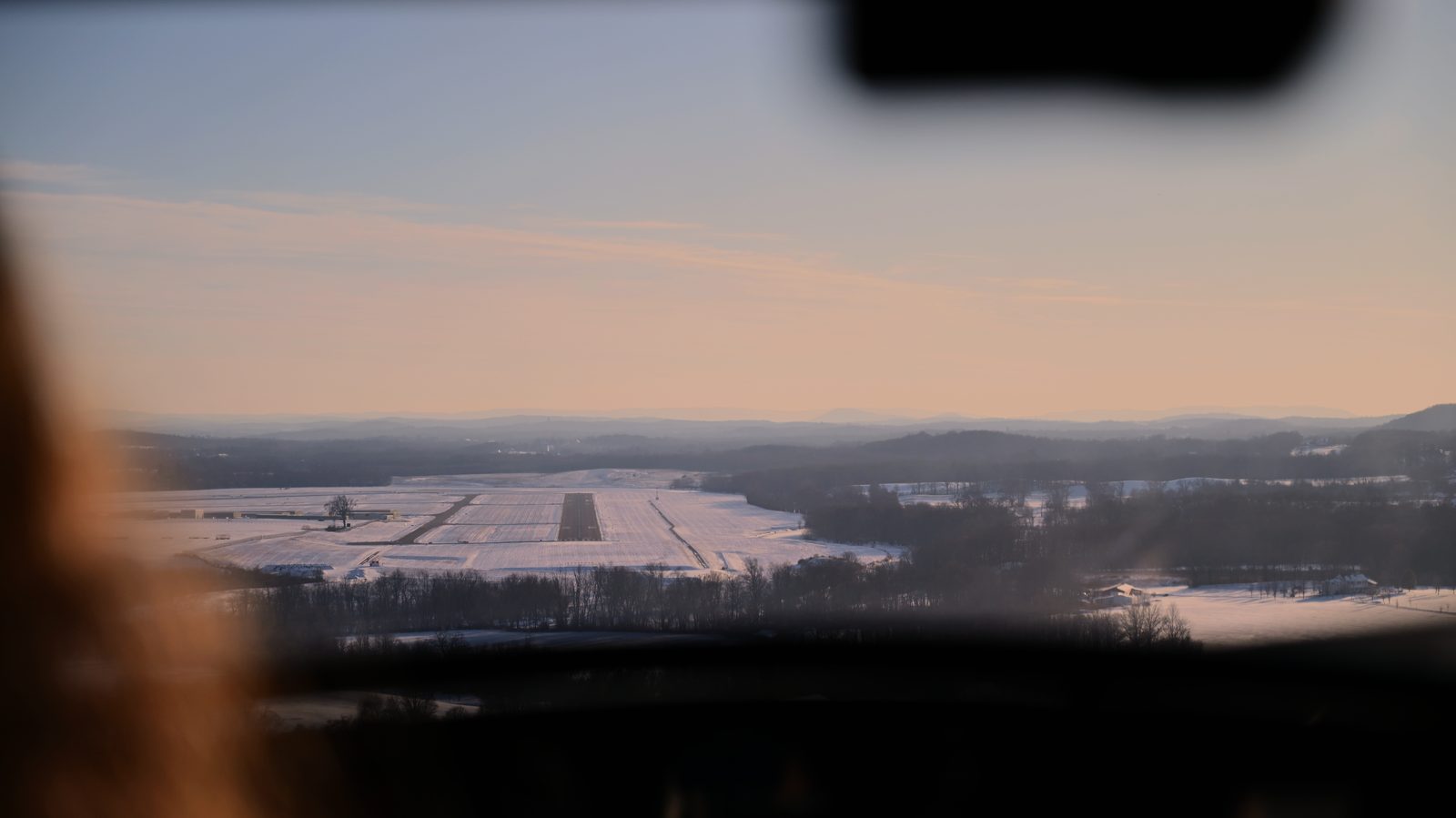 Snowy runway seen through the windscreen on approach at sunrise