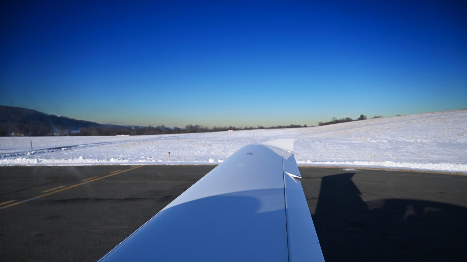 White wing over a snow-covered landscape under a blue sky
